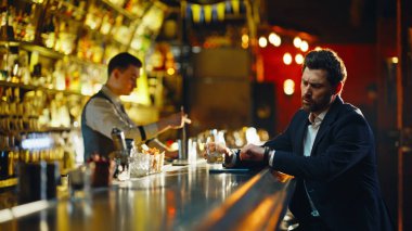 Loş bar tezgahında oturup içki içen yalnız bir adam sessizce yakın plan yapıyor. Saati kontrol eden sarhoş adam buluşmaya gelmedi. Üzgün erkek konuk kredi kartıyla ödeme yapıyor.
