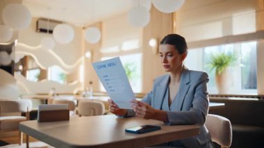 Restoran misafiri menüyü okuyup rahat masada sessizce oturarak siparişi hazırlıyor. Kafeteryada güzel bir kadın ziyaretçi. Kendine güveni tam bir iş kadını. Tabakları inceliyor, kafeteryada bekliyor.