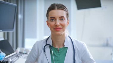 Klinikte steteskopla poz veren gülümseyen doktor portresi. Yakın plan başarılı kadın modern hastanede kamera arıyor. Profesyonel sağlık uzmanı jinekolog mesai sırasında ara verdi.