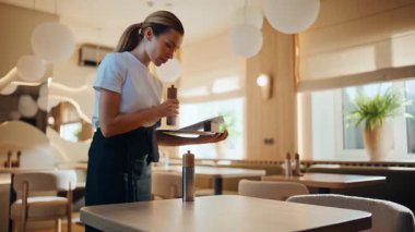 Ciddi restoran çalışanları bulaşık servisini yakın çekime koyuyor. Genç servis elemanı müşteriler için kafeterya hazırlıyor. Odaklanmış kadın garson sabahları boş kafede tek başına dikkatli çalışıyor.