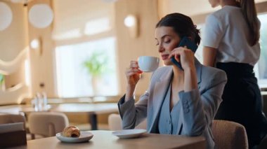 Kendine güveni tam bir yönetici, kafeteryayı arıyor. Küçük masada tek başına oturuyor. Gülümseyen iş kadını kafede cep telefonu bekletme toplantısı hakkında konuşuyor. Samimi bir restoranda cep telefonuyla konuşan zarif bir işyeri sahibi.