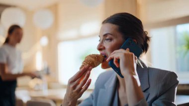 Modern kafeteryada cep telefonuyla konuşan şık bir bayan. Lüks kafede resmi takım elbiseli, gülümseyen şık bir kadın cep telefonuyla konuşuyor. Zarif bir iş kadını akıllı telefonu arıyor ve tek başına dinleniyor.