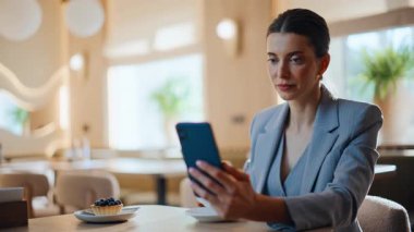 Kendine güvenen bir bayan cep telefonuna mesaj atıp samimi bir restoranda kahve fincanı içiyor. Gülümseyen genç bir kadın akıllı telefonu masaya koyuyor ve tek başına oturuyor. Kafeteryadaki mutlu patron cep telefonuna bakıyor.