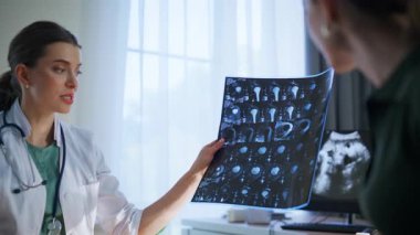 Röntgen sonuçlarını açıklayan bir pratisyen. Mutlu hasta, olumlu kadın doktoru ziyaret ettiğinde gülümsüyor. Travma taraması ve başarılı rehabilitasyonu tartışan neşeli bir uzman. Tıbbi servis kavramı