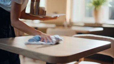 Garson, restoranı temizliyor. Beyaz yüzey kafeteryasını ıslak bezle temizleyen ciddi bir kadın işçi. Konukseverlik ortamında temizlik yapmaya çalışan odaklanmış bir kadın.