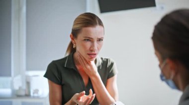 Klinik randevusunda sağlık sorunu olan bir kadın. Portre hastası, sağlık hizmetlerinde ağrıdan şikayetçi. Klinikteki sağlık muayenesinde bilinmeyen bir doktorla konuşan genç bayan.