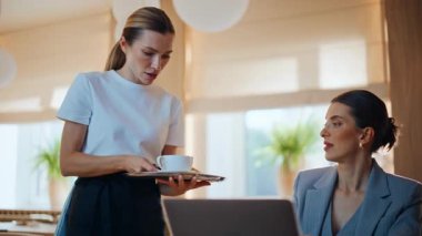 Gülümseyen garson yakın planda hafif restoranda kahve getiriyor. Cafe 'de laptopla yemek yiyen kendine güvenen zarif bir kadın. Resmi takım elbiseli iş kadını öğle yemeğinin tadını çıkarıyor bilgisayarla oturuyor.