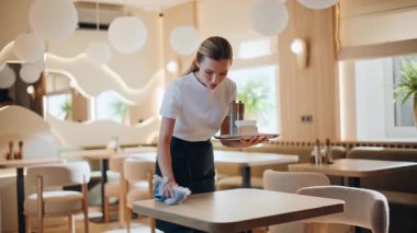 Kafe barında yüzeyleri silen özenli bir kadın. Genç pozitif barista, modern hafif restoran içlerine gülümseyen tabaklar koyuyor. Rahatlamış garson sabah çalışıyor. Halka hizmet mesleği kavramı