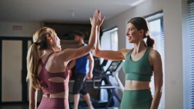 İki sporcu kadın aktif antremandan sonra 5 dakika çalışıyor. Modern spor salonunda takım çalışmasından zevk alan gülümseyen bir çift. Mutlu formda sporcular modern fitness kulübünde birlikte olmaktan memnunlar.