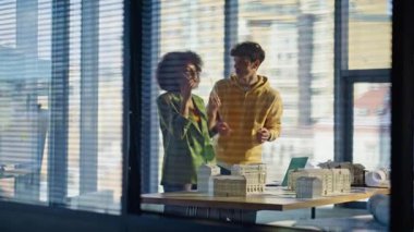 Takım mimarları akıllı telefondan konferans odasında mimari proje sorununu tartışıyorlar. İki çok ırklı mühendis cep telefonunu arıyor. İş arkadaşları telefondan şikâyet ediyor..