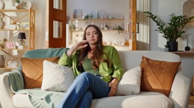 Modern oturma odasındaki üzgün kız sorunları. Ciddi bir genç kadın, baş ağrısına odaklanmış migren rahat koltukta tek başına oturuyor. Endişeli esmer kafa ovma hafta sonu düz