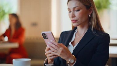 Restoran masasında kahve fincanı yakın çekimde cep telefonuyla mesajlaşan zengin kadın. Kafeteryada cep telefonunu kontrol eden zarif bir iş kadını. Modern lüks kafede akıllı telefonlara mesaj atan muhteşem bir kadın..