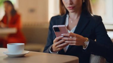 Modern kafeteryada cep telefonu izleyen gülümseyen bayan. Cep telefonu bankacılığı uygulamasına bakan pozitif iş kadını kahve fincanı ile kafeterya masasında oturuyor. Evde cep telefonu mesajı okuyan zarif bir kadın.