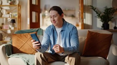 Mutlu, rahat bir adam cep telefonu ekranında evde dinleniyor. Gülümseyen öğrenci rahat koltukta akıllı telefon sosyal ağlarına göz atıyor. İnternette cep telefonu alışverişi yapan yakışıklı bir adam.