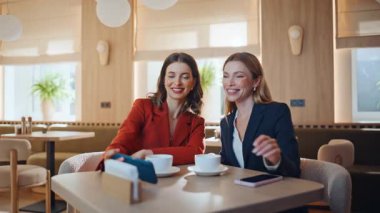 İki iş kadını, kafeterya masasının yakınında selfie cep telefonu yapıyor. Kahvehanedeki dostça buluşmada akıllı telefondan fotoğraf çeken zarif kadınlar. Neşeli kankalar fotoğrafı..