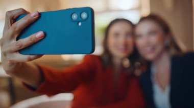 Yakın plan kadınlar modern restoranda otururken akıllı telefondan selfie çekiyorlar. Arkadaşça bir toplantıda cep telefonu fotoğrafı için gülümseyen zarif bayanlar. Kafede cep telefonuyla fotoğraf çeken mutlu arkadaşlar..