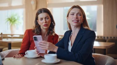 Stresli ortaklar öğle yemeğinde cep telefonu oturma lokantası okuyorlar. Duygusal iki iş kadını cep telefonu mesajında reddediliyor. Sinirli bayanlar akıllı telefondan endişeli görünüyorlar..