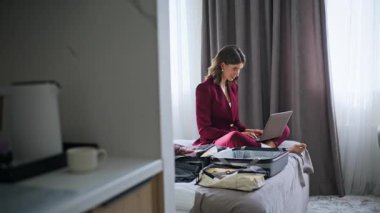 Otel odasında çalışan iş kadını rahat bir yatakta bacak bacak bacak üstüne atmış oturuyor. Gülümseyen kadın, lüks bir motelde kontrol ettikten sonra bilgisayarını kapatıp e-postayı bitiriyor. Başarılı bayan daktilo bilgisayarı