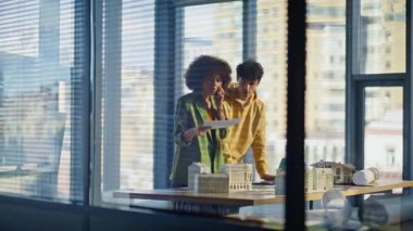 Endişeli yöneticiler cep telefonuyla toplantı odasında inşaat projesinin hatasını tartışıyor. Sorunlu Afrikalı Amerikalı kadın, erkek meslektaşıyla evraklarını tutmak için arıyor. Hüsrana uğramış mimarlar.