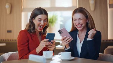 Duygusal iki iş kadını, kafeye yakın bir yerde cep telefonu görüntüsü vererek başarıya ulaşıyor. Cep telefonlarının galibiyete tepki vermesini izleyen aşırı mutlu iş ortakları. Neşeli arkadaşlar akıllı telefonlardan harika haberler okuyor..