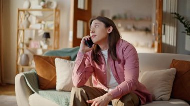 Rahat adam akıllı telefondan konuşuyor. Rahat koltukta gülüyor. Yakın plan. Pozitif adam cep telefonuyla haberleri tartışıyor rahat koltukta oturuyor. Gülümseyen esmer içeride dostça sohbet eder.