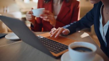 İş ortakları kafeteryadaki iş toplantısında dizüstü bilgisayarı izliyorlar. Restoranda iş birliği yapan iki iş kadını bilgisayara göz atıyorlar. Kahve fincanı tutan bayan meslektaşımla işbirliği yapıyor..