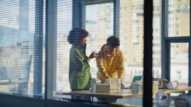 İnşaat şirketinin toplantı odasında iş birliği yapan bina tasarımcıları arıyor. Afrika kökenli Amerikalı bir kadın cep telefonuyla konuşuyor ve iş arkadaşıyla çalışıyor. Akıllı telefondan danışmanlık yapan takım mimarları.