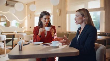 Kahve molasında sohbet eden meslektaşlar samimi kafeteryalarda yan yana oturuyorlar. Sıcak içecek içen iki kadının restoranda keyifli sohbetler etmesi. Zarif iş kadınları işi tartışıyor.