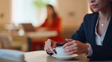 Kadın elleri kafeterya masasından kahve fincanı alıyor. Akıllı telefondaki zarif bayan, kafeteryada iş görüşmesi için bekliyor. Kendine güvenen iş kadını rahat bir restoranda içki içiyor..