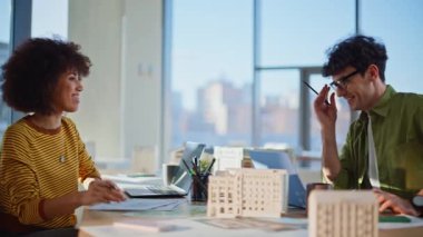 Emlak uzmanları inşaat bürosunun kapanmasında fikir alışverişinde bulunuyorlar. Gülümseyen çok ırklı meslektaşlar dostça sohbetin tadını çıkarıyorlar. İki emlak yöneticisi iş yerinde iletişim kuruyor..
