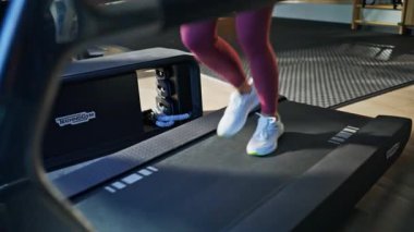 Spor giyim kuşamında koşucu eğitimi alan enerjik bir koşucu. Günlük antrenmanlarda koşu bandında koşan motive bir kadın. Sportif bir bayan sağlıklı ve güçlü bir vücuda sahip olmak için egzersiz yapıyor..