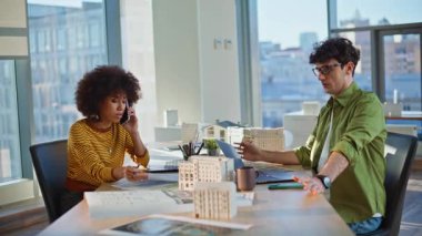 Ofis inşaatında cep telefonuyla konuşan hayal kırıklığına uğramış inşaatçılar. İki melez mimar cep telefonuyla tasarım projesini tartışıyor. Afro-Amerikalı kadın akıllı telefondan şikayet ediyor..