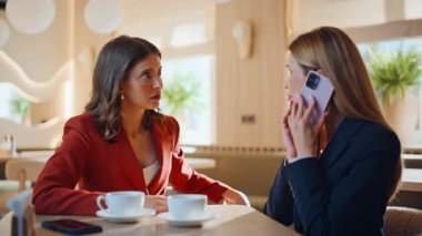 İş arkadaşları, kafede kahve molasında oturan cep telefonundan endişeli. Stresli kadın arkadaşınla olan hoşnutsuz akıllı telefon konuşmanı bitir. İş arkadaşları kafeteryadaki telefon konuşmalarından bıktı