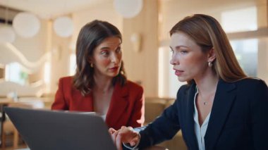 Modern restoranın yakın planında dizüstü bilgisayarla ilgili verileri tartışan zarif iş arkadaşları. Kafede bilgisayar arayan başarılı iş kadınları. Kafeteryada anlaşmada çalışan kendine güvenen iki kadın..