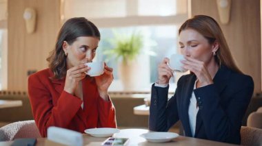Modern kafeteryada kahve içen kızlar. Sıcak kahve evinde kapuçino içen gülümseyen kadınlar. Cafe 'de dostça iletişim kuran zarif iş kadınları.