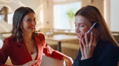 Gülümseyen meslektaşlarım kafeteryadaki harika haberleri duymaktan memnuniyet duyuyorlar. İki kadının telefonda konuştuktan sonra beş dakika konuşarak başarıyı yakalaması heyecan verici. Duygusal iş kadınları akıllı telefon konuşmalarından keyif alırlar..