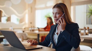 Restoran masasında bilgisayarlı akıllı telefondan konuşan bir iş kadını. Zarif kadın yönetici kafede cep telefonuyla sipariş veriyor. Mutlu iş kadınlarının telefon görüşmesi bilgisayarları vardır.