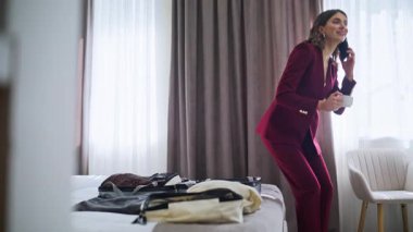 Otel misafirini arayıp rahat yatak odasında kahve içmek. Gülümseyen iş kadını cappuccino yudumluyor lüks bir otel odasında cep telefonundan konuşuyor. Kendine güvenen bir bayan iş seyahatinde iş konuşur.