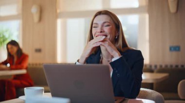 Modern kafenin iç kısımlarında oturan profesyonel kadın, dizüstü bilgisayarında sevinç dolu bir mesaj veriyor. Gülümseyen heyecanlı bayan yönetici harika bir iş teklifi alıyor. Restoranda internet haberlerinden memnun olan mutlu iş kadını.