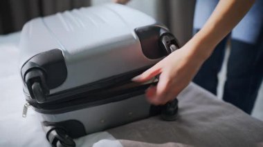 Kadın elleri otel yatağında bavulları boşaltıyor. Gülümseyen bayan turist otel odasına vardıktan sonra bavullarını çıkarıyor. Mutlu kız gezgin modern dairede tatilin tadını çıkarıyor..