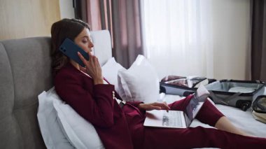 Kendine güvenen bir bayan otel odasını arayıp laptopun kapanış raporunu kontrol ediyor. Başarılı bir iş kadını iş gezisinde beyaz yataklı cep telefonuyla konuşuyor. Motelde akıllı telefondan konuşan güzel bir kadın.