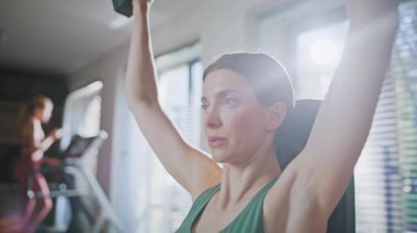 Spor salonunda dambılla çalışan yakın plan kadın. Fitness kızı spor kulübünde aktif antrenman yapıyor. Atletik kadın ağırlık egzersizi yapıyor. Güçlü motivasyona sahip sporcu kadın el kaslarını çalıştırıyor..