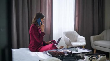 Meşgul iş kadını otel odasında akıllı telefon görüşmeleri yapıyor. Kendine güvenen kadın yönetici telefon siparişi veriyor bilgisayarın web sitesini tarıyor. Girişimci iş gezisine çağırıyor.