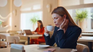 Modern kafeteryada espresso içen zarif bir iş kadını. Kendine güvenen iş kadını akıllı telefonu kontrol ediyor kafede sıcak kahve içiyor. Başarılı kadın yönetici iş molası mesajını okumayı seviyor