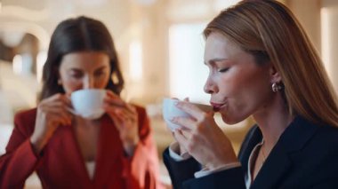 Kafeteryadaki dostça buluşmada kahve içen şık kankalar. Modern kahvehanede nefis sıcak içeceklerin tadını çıkaran iki kadın. Kafede fincanlardan yudumlayan neşeli arkadaşlar.