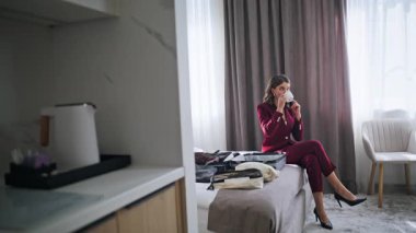 Otel misafiri rahat bir yatakta cep telefonuyla konuşuyor. Zarif bir iş kadını, yatak odasında kahve içiyor, cep telefonunu arıyor. Başarılı bir bayan iş gezisinde espresso yudumlarken akıllı telefondan konuşuyor..