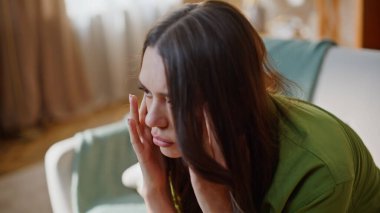 Kanepede rahat bir şekilde oturan yorgun kadın stresin yakın çekim yaptığını hissediyor. Evde rahat bir koltukta sorunlarla boğuşan yorgun bir kadın. Stresli kız baş ağrısı çeken kafaya dokunuyor.