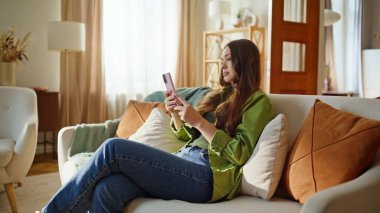 Bej kanepede bekleyen esmer görünümlü, soğuk bir cep telefonu. Oturma odasında sosyal medyayı okumaktan sıkılmış rahat bir kadın. Sakin kız dinleniyor. Teknoloji ve insanlar kavramı