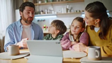 Muhabbet eden aile tableti arıyor. El hareketleriyle sabah mutfağını kapatıyorlar. Dört kişi içeride duygusal olarak rahatlatıcı konuşuyor. Web kamerasına bakan meraklı çocuklar. Modern teknoloji yaşam tarzı