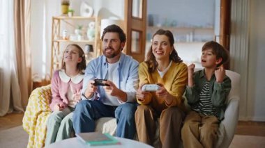 Neşeli bir aile kanepede oturup video oyunu oynuyor. Zafer yarışmasını kutlayan dört üye heyecanlı. Ebeveynler, çocuklar konsollara baskı yapıyor ve oyun oynamaktan zevk alıyorlar. Dijital eğlence